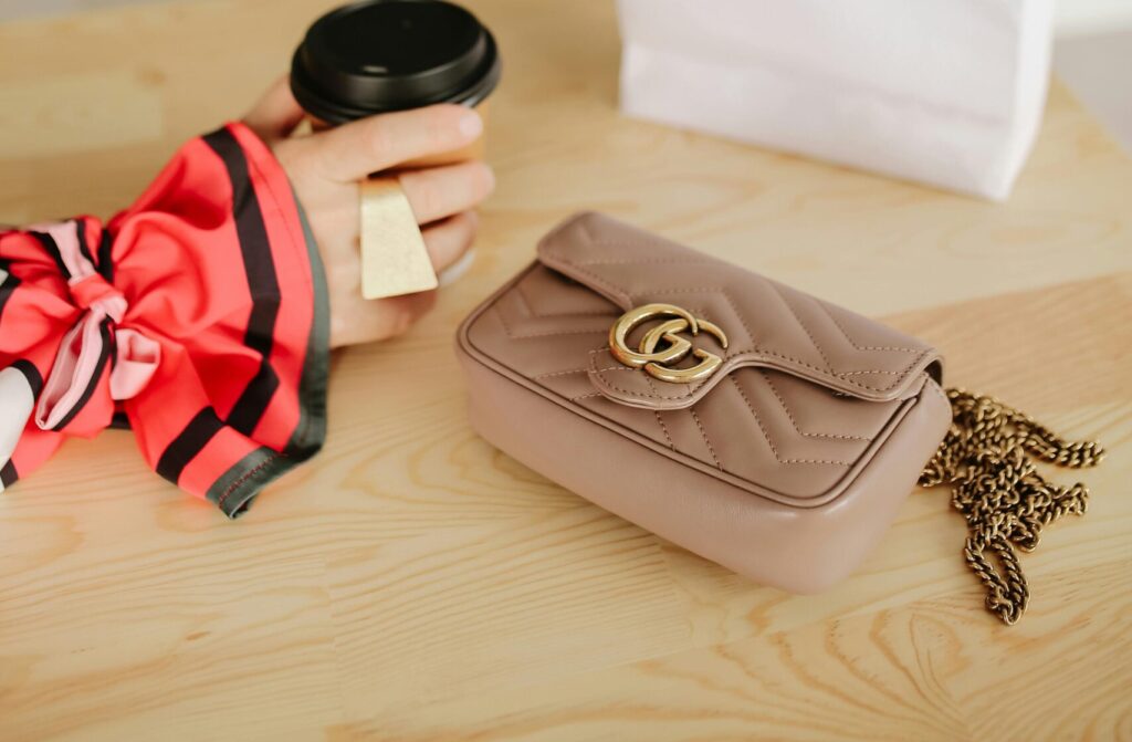 Elegant scene with Dior bag, flowers, coffee cup, and luxurious handbag.