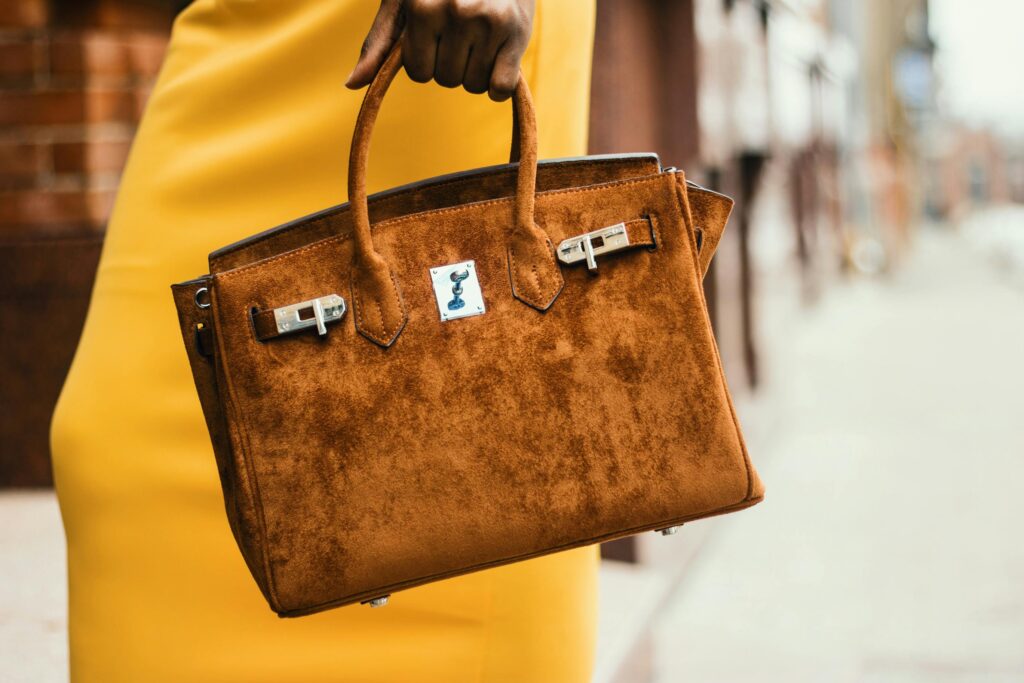 Chic brown leather handbag held by a fashionable woman in a vibrant cityscape.