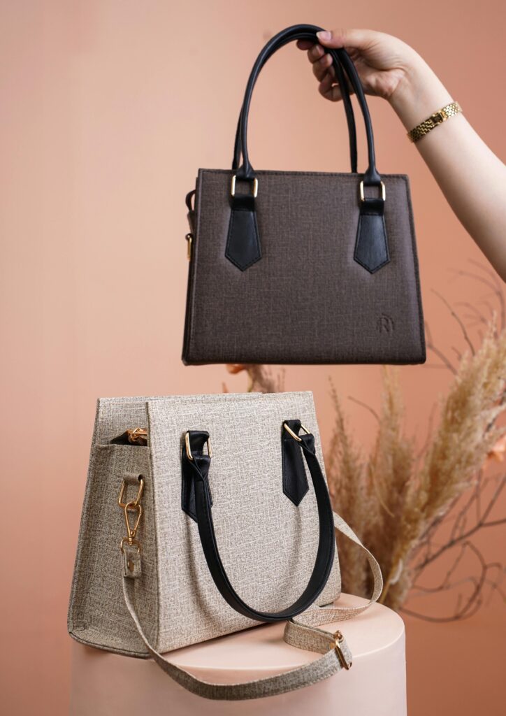 Display of two stylish handbags with a natural backdrop in a studio setting.